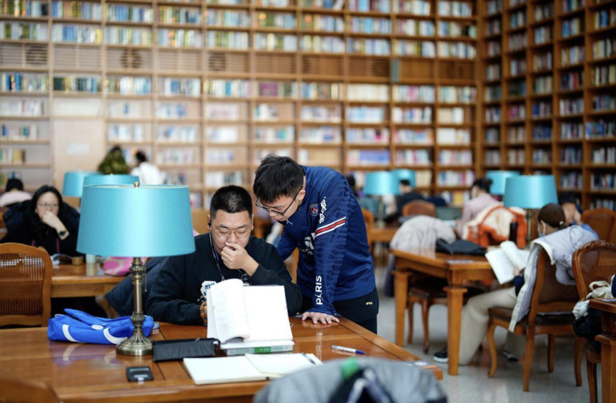 春节假期，两位同学在图书馆内轻声交流书中的问题。 赵亮摄