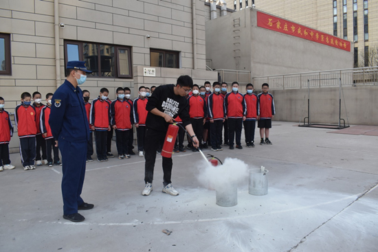 在消防员指导下，师生们学习干粉灭火器的使用。 陈园青摄