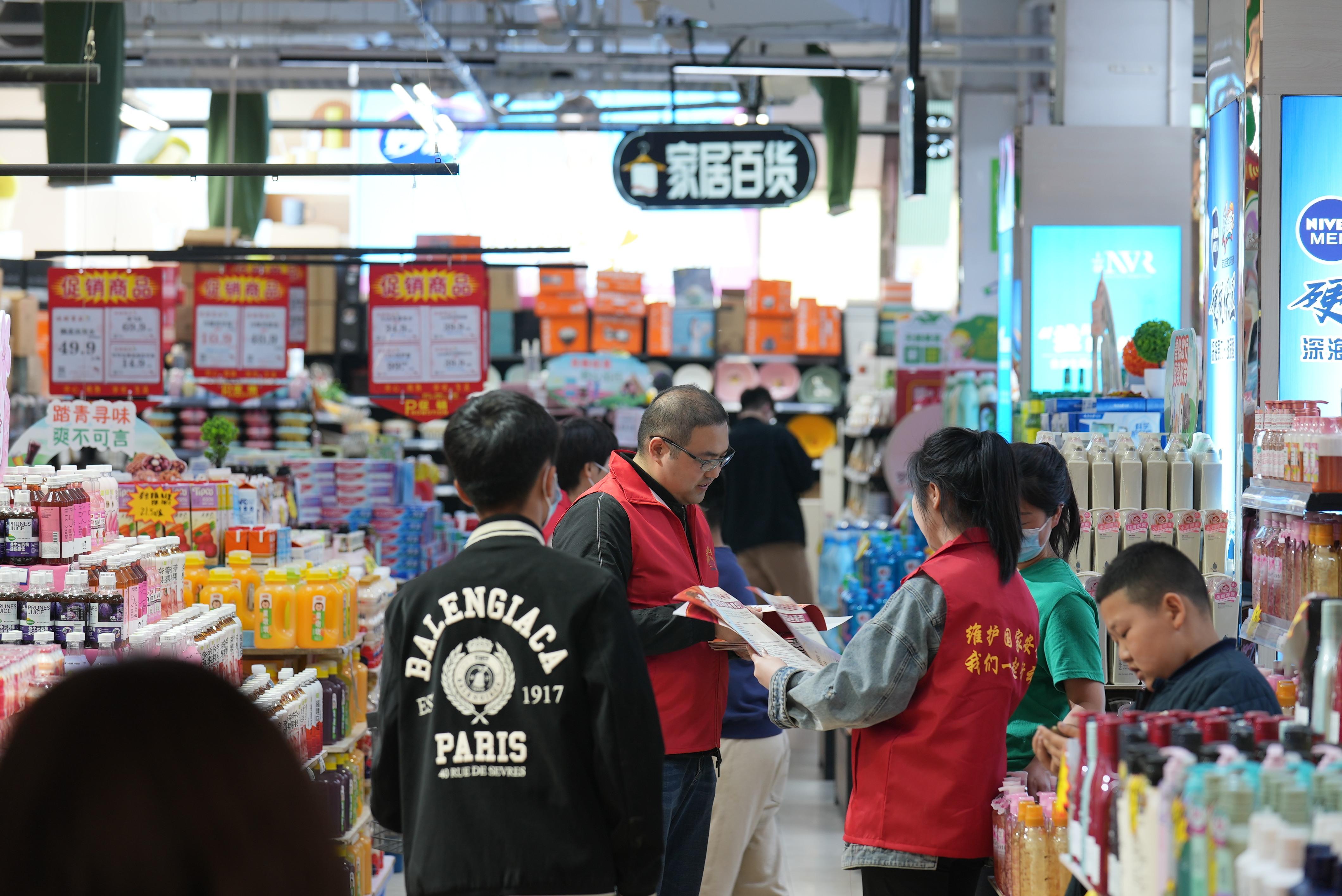 4月15日,在河北保定白沟新城天弈商厦,志愿者向商超工作人员宣传国家安全相关法律法规。 杜雨佳摄
