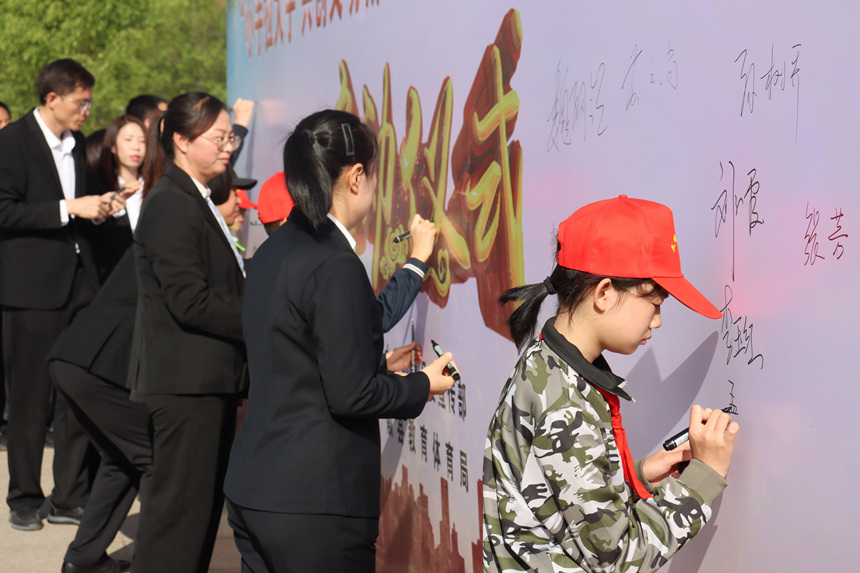 活动仪式上，学生和老师、家长一起在背景墙上签字。 彭锦帅摄