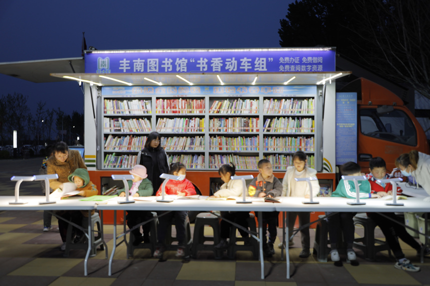 学生在丰南图书馆“书香动车组”流动服务车前翻阅图书。 毕帅摄