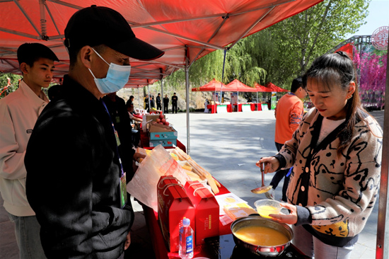 農產品展銷會上，游客在品嘗熬制的小米粥。 張明月攝