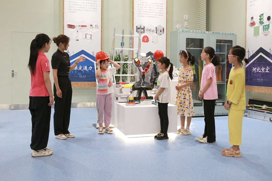在高阳县庞家佐镇电器电料展馆，同学试戴安全帽。 冉宁摄