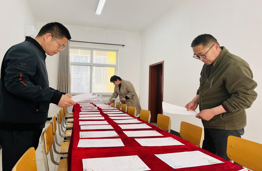 涞水县娄村镇娄村评委老师评比学生书法作品。 李金璐 摄