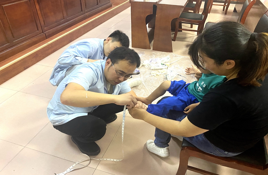 工作人员为残疾儿童测量脚长脚宽等尺寸 。 唐县融媒体中心供图