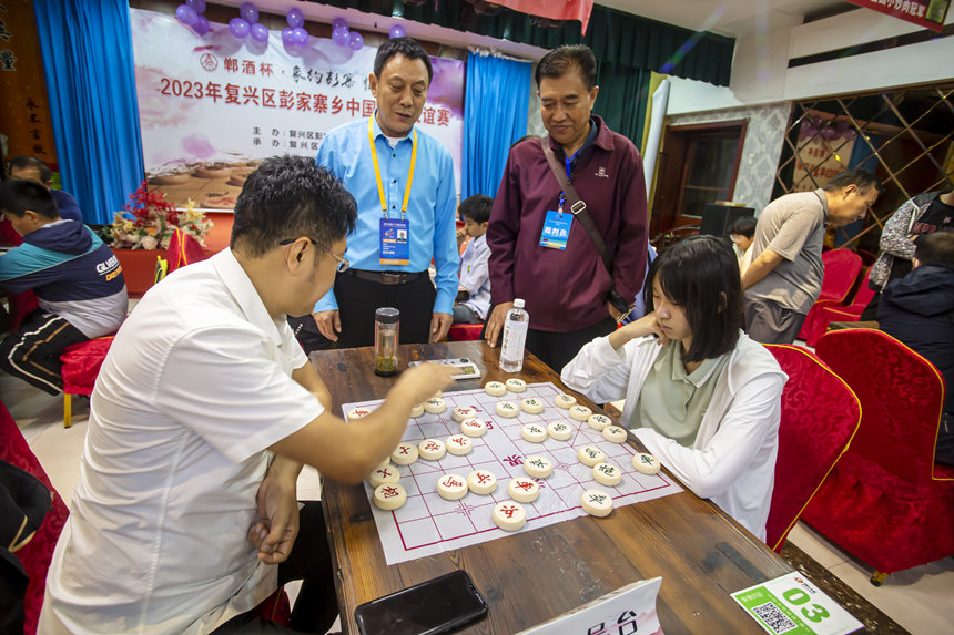 河北省运会青少年组象棋赛女子甲组冠军刘校汝（右）在与彭家寨乡群众比赛中。 聂长青摄