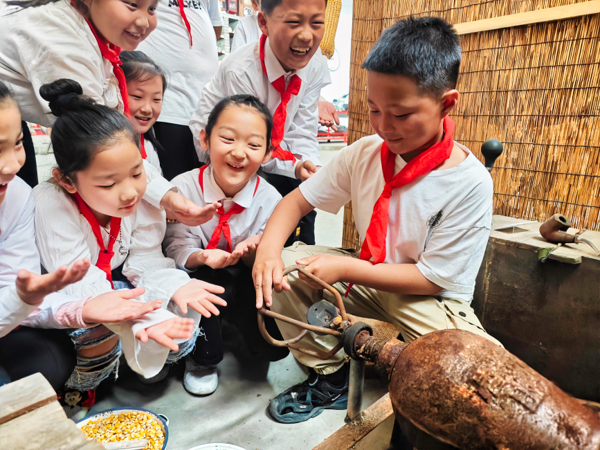 在唐坊民俗博物馆,唐坊中心小学的学生在体验爆米花机制作爆米花。 张杰摄