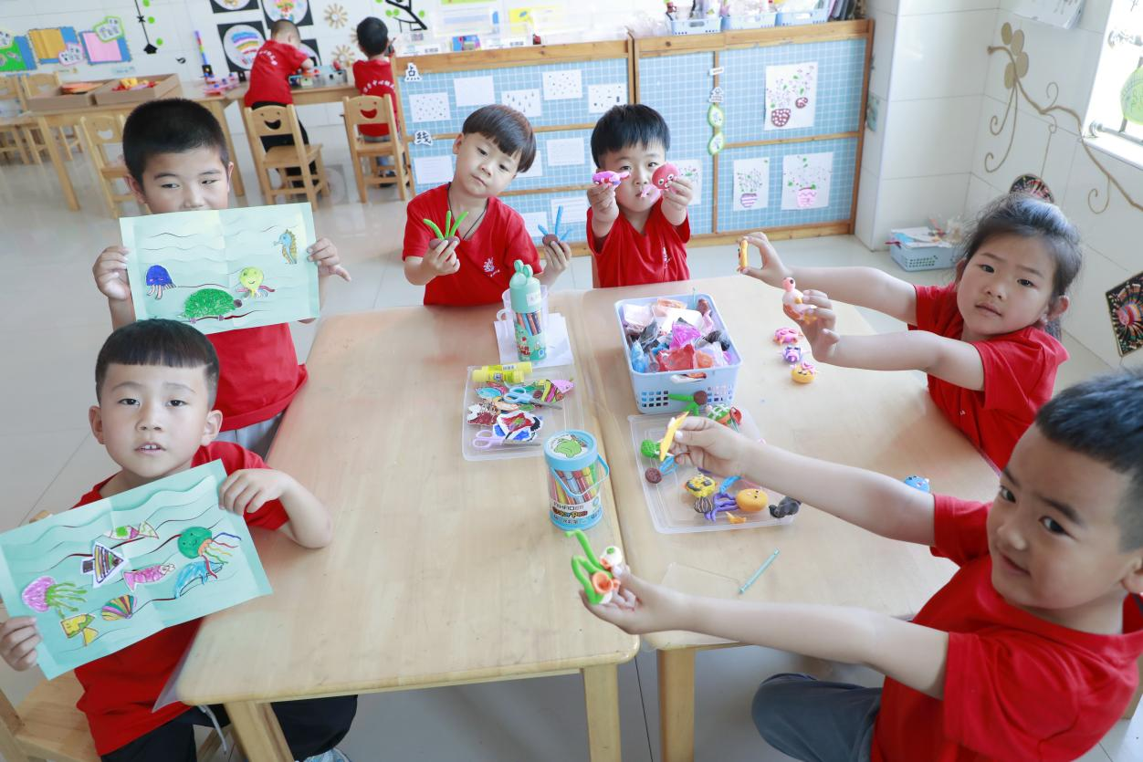 河北省唐山市丰南区黑沿子中心幼儿园的孩子们正在展示制作的海洋主题手工作品。 陈军摄