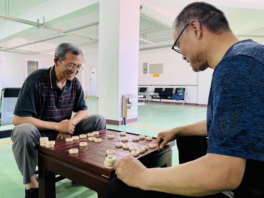 老人们正在社区日间照料服务中心活动室内下象棋。 李金璐摄
