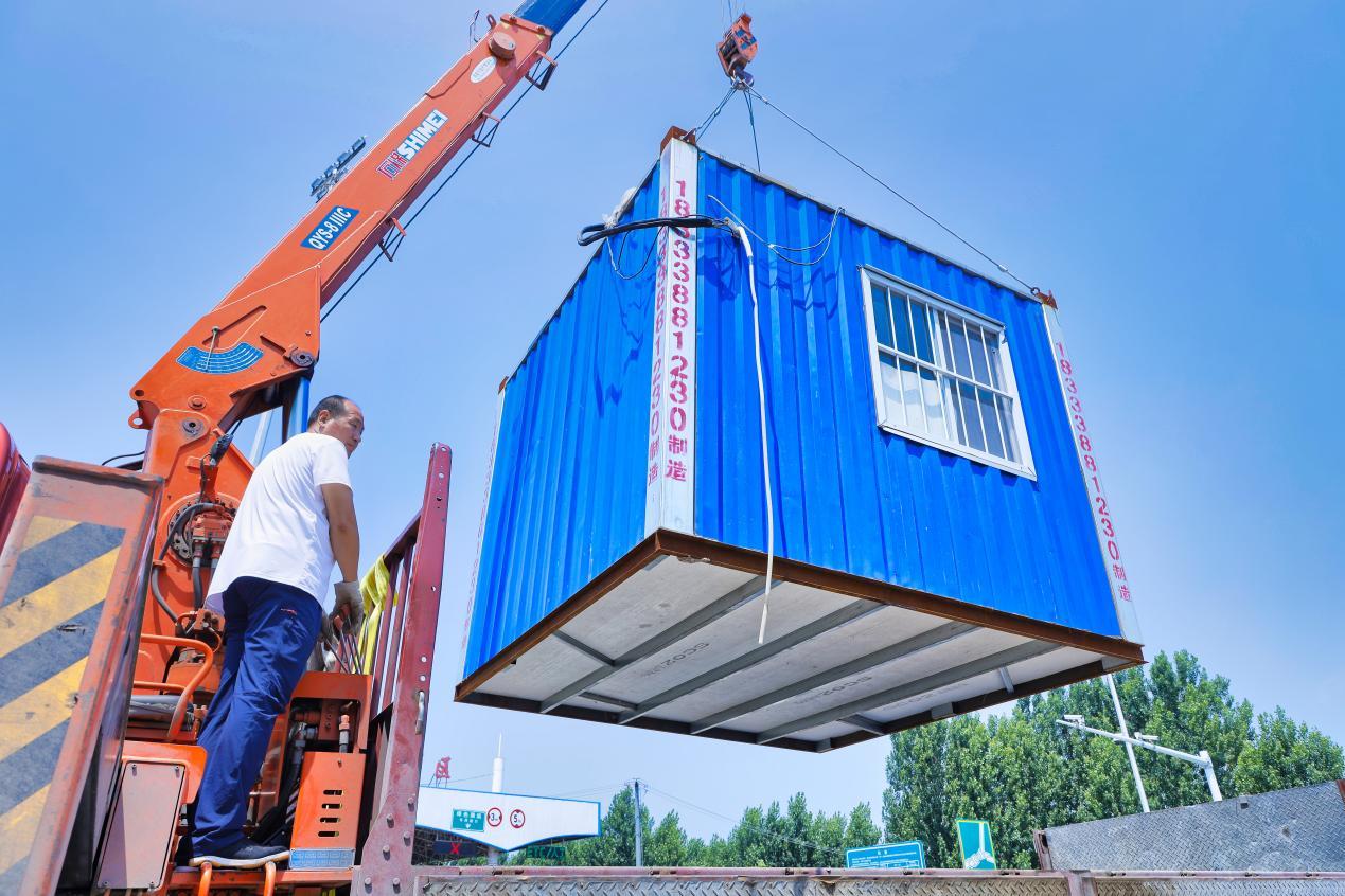 在河北省唐山市丰南工业区高速出口,工作人员正在吊卸集装箱,设置农机跨区作业接待服务站。 毕帅摄