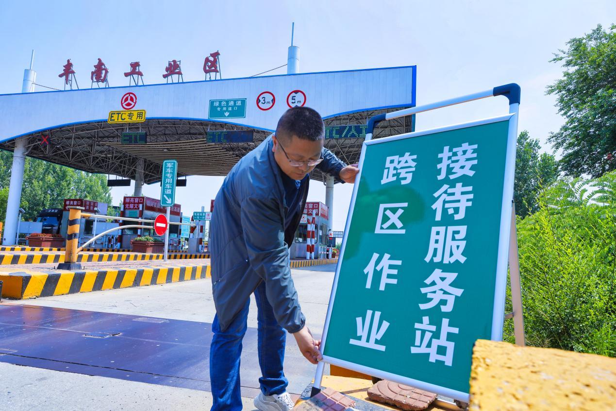 在河北省唐山市丰南工业区高速出口,工作人员正在设立跨区作业接待服务站指示牌。 毕帅摄
