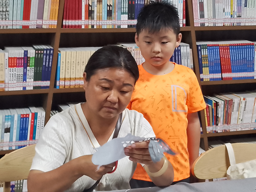 小朋友认真跟剪纸艺人学剪纸。 韩芳摄