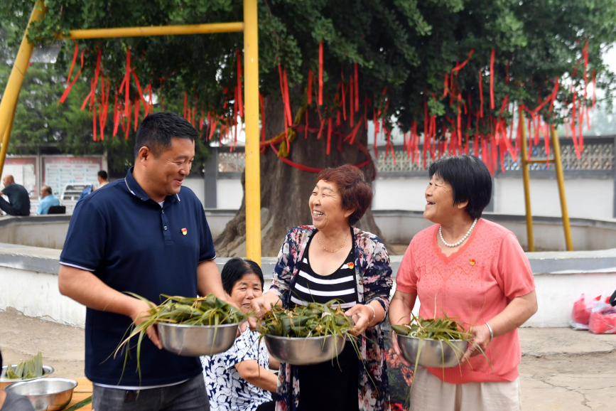 6月19日,在遷安市蔡園鎮馬官營村,黨員志願者將包好的粽子送給村內低保戶。 彭月娟攝