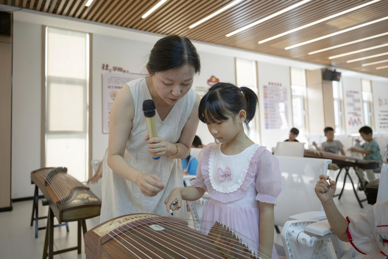 在爱心暑托班古筝课上，孩子们在老师的指导下练习弹奏指法。 翟子阳摄