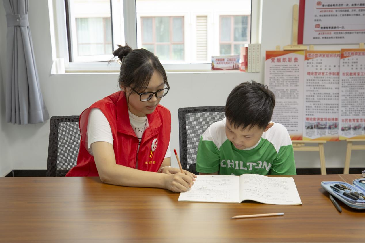 在爱心暑托班课业辅导课上,孩子们在写作业时遇到问题向老师请教。 翟子阳摄