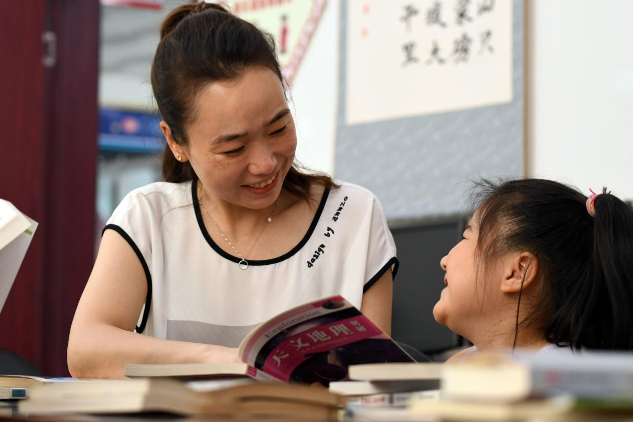 在文安縣國泰西道社區居委會宣傳文化活動室，家長陪孩子閱讀書籍。 鄭佳慶攝