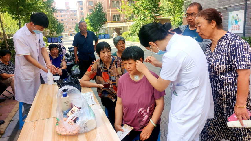 医务人员为居民进行耳针治疗。 常彪摄
