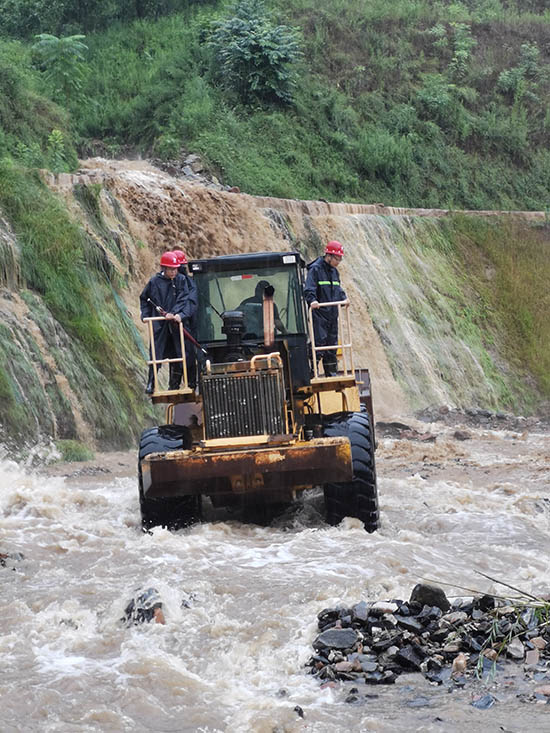 7 月30日，因暴雨冲刷，道路坍塌，国网武安市供电公司工作人员克服困难，乘坐铲车前往古武当山地区进行电力抢修。 徐建锋摄