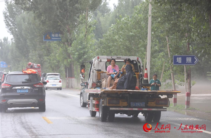 8月1日傍晚,在涿州市刁窝镇塔照村,救援人员正在转移受灾群众。 人民网 李兆民摄