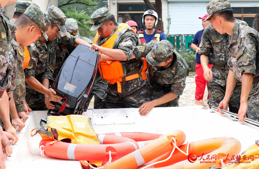 8月2日上午，在涿州市107國道受災路段，數十名武警某部官兵到達現場准備為受困群眾送去食品、飲用水。圖為武警官兵正在搬運快艇。 宋燁文攝 