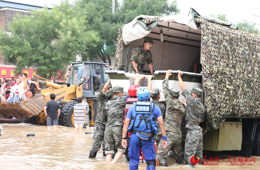 8月2日上午，在涿州市107国道受灾路段，数十名武警某部官兵到达现场准备为受困群众送去食品、饮用水。图为武警官兵正在搬运快艇。 宋烨文摄