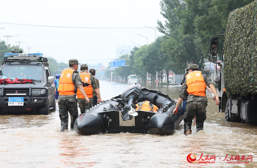 8月2日上午，在涿州市107国道受灾路段，数十名武警某部官兵到达现场准备为受困群众送去食品、饮用水。图为武警官兵正在搬运冲锋舟。 宋烨文摄