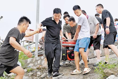 8月3日，涞水县自然资源和规划局党员服务队和三坡镇当地村民一起搬运发电机。 河北日报记者 史晟全摄　　