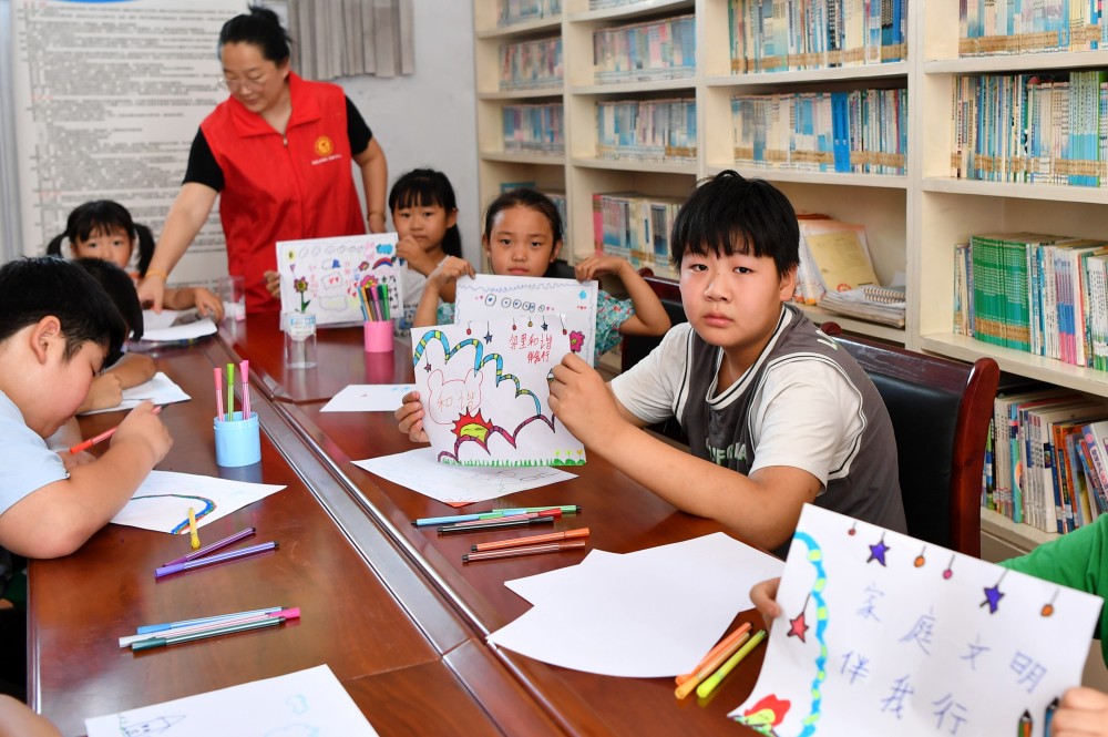 8月10日，在迁安市沙河驿镇唐庄子村农家书屋内，孩子们展示画好的“家庭文明“主题画。 彭月娟摄