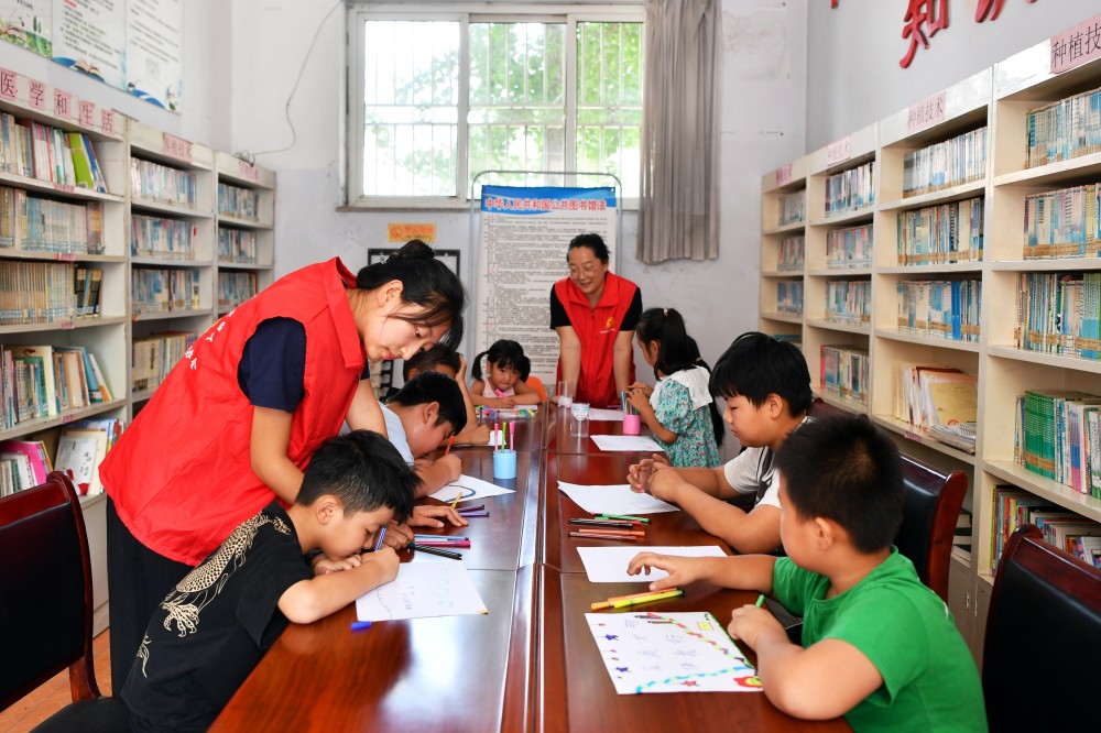 8月10日，在迁安市沙河驿镇唐庄子村农家书屋内，志愿者陪儿童绘制“家庭文明“主题画。 彭月娟摄