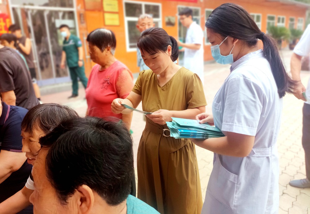 工作人员向居民发放健康知识小册子。 柴静摄