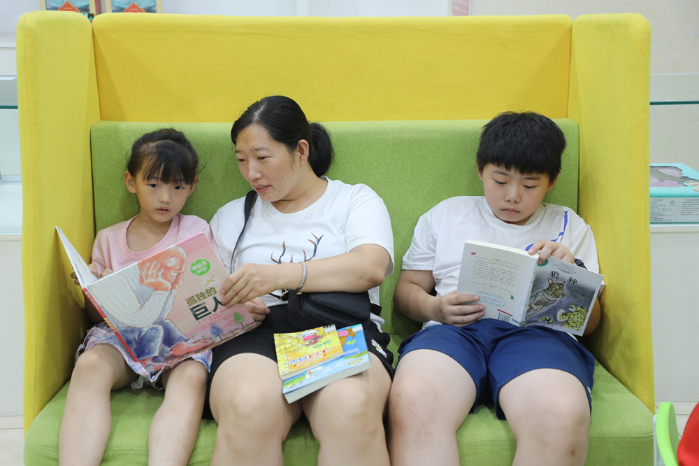 桥西区图书馆内，家长陪伴孩子一起阅读。 董璐摄