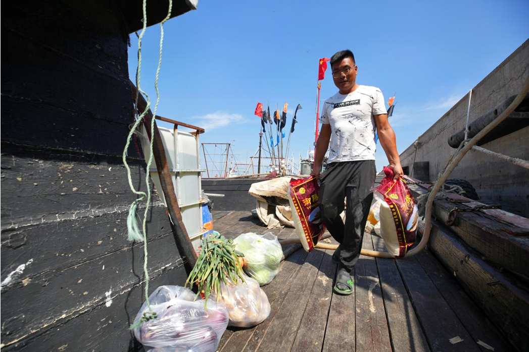 在黑沿子渔港码头,渔民正将生活物资搬上船,为为期半月的海上作业做准备。 李福政摄