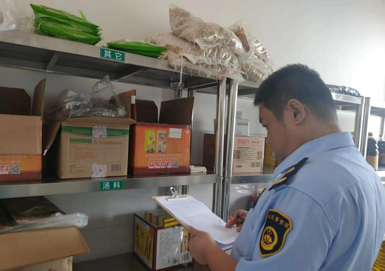 工作人員查看食品安全相關制度落實情況。 翁玉群攝