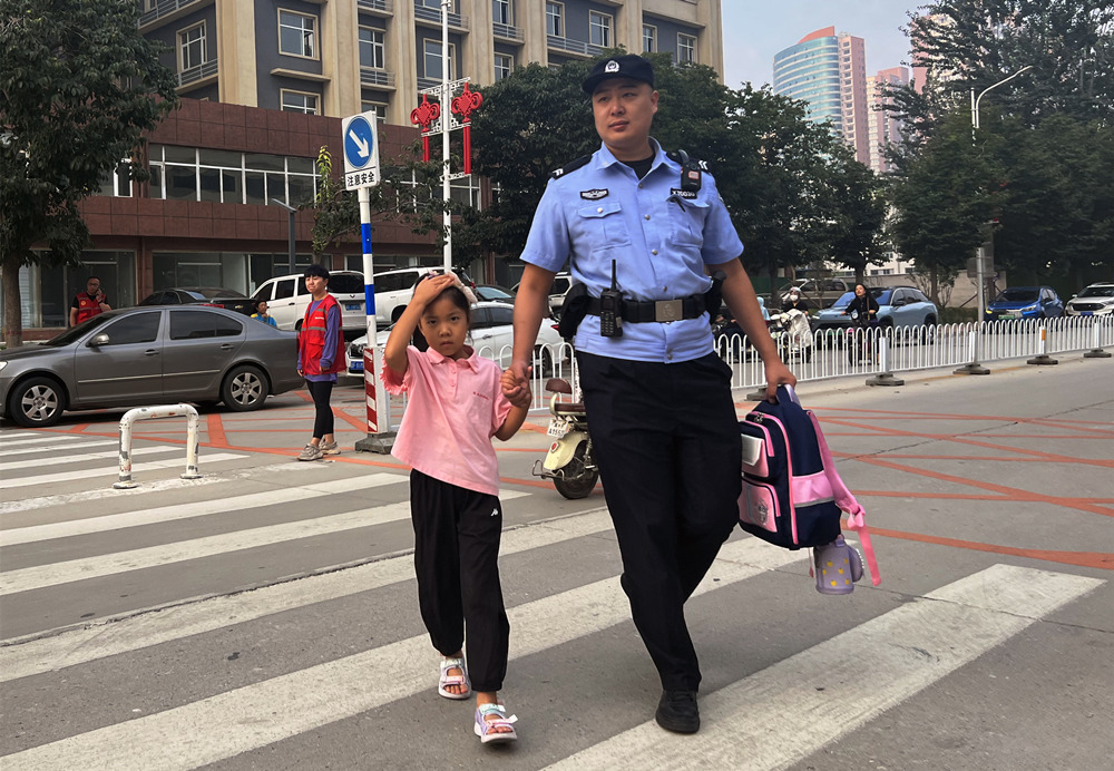 上学高峰时段，民警护送学生通过人行横道。 刘玮摄
