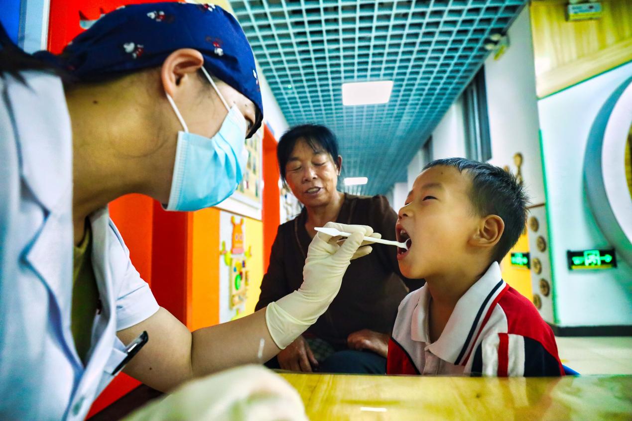 在河北唐山丰南区岔河镇中心幼儿园，牙医正在为老人和小朋友检查牙齿健康情况。 毕帅摄