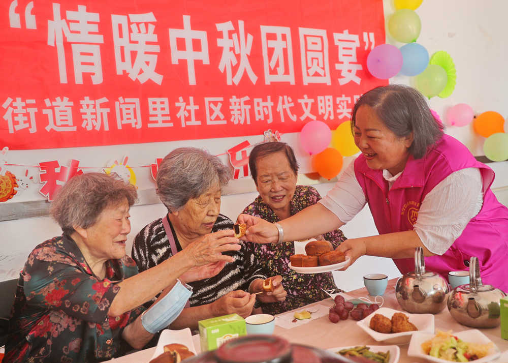 海港区新闻里社区志愿者为老人送上月饼。 曹建雄摄