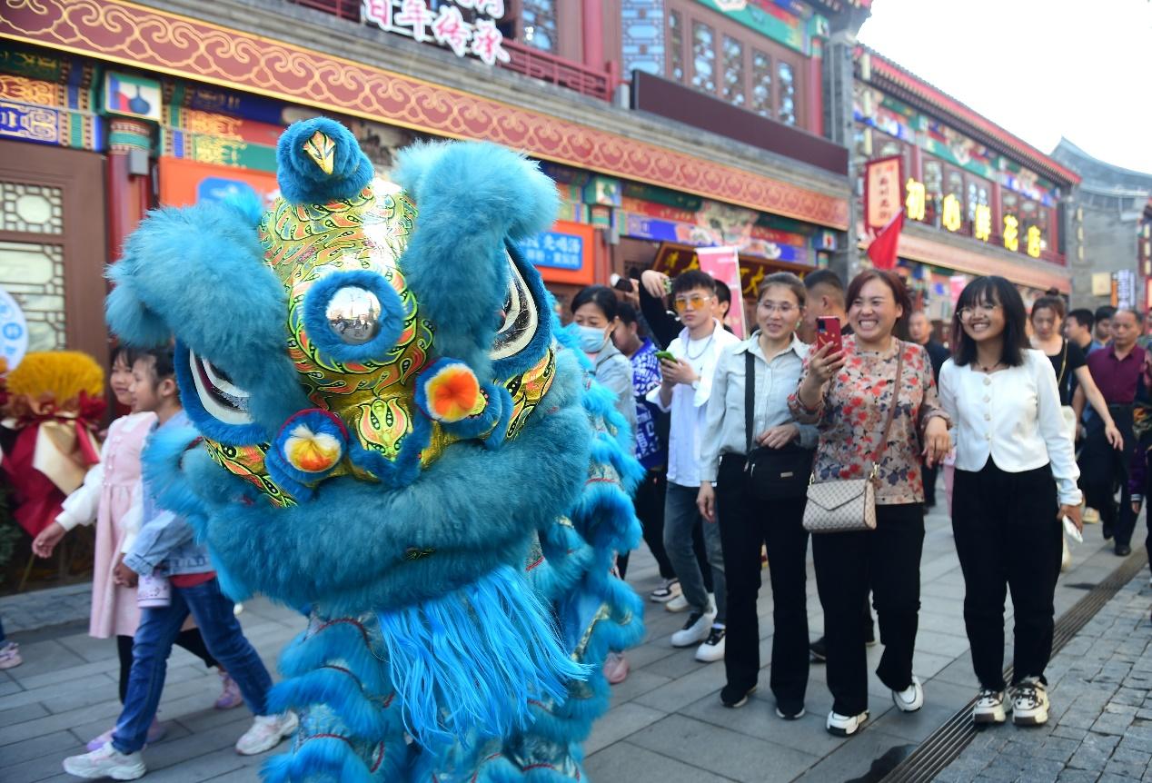 调皮的舞狮在沧州南川老街与游客互动。 傅新春摄