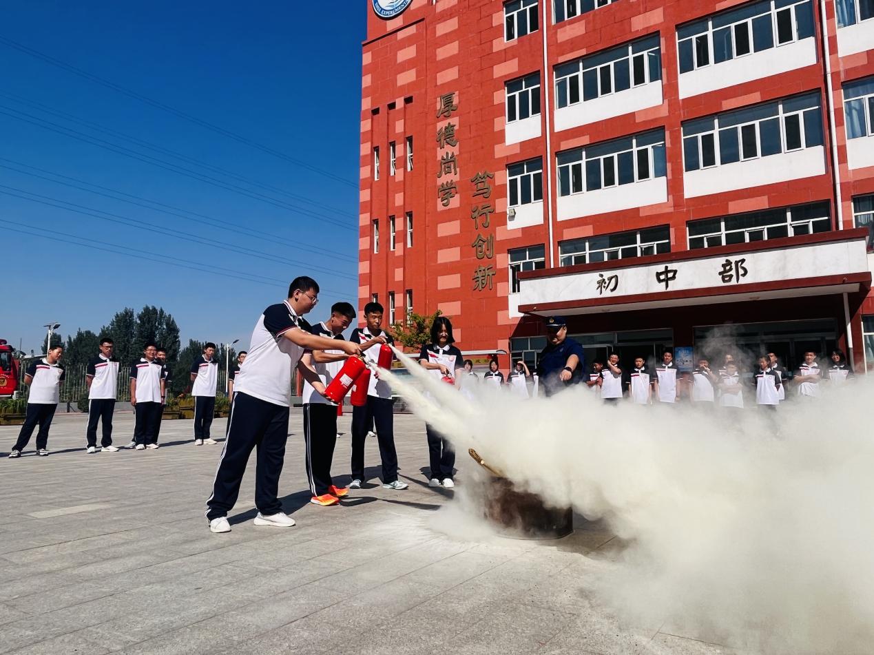 消防员指导学生灭火器使用方法。 李金璐摄