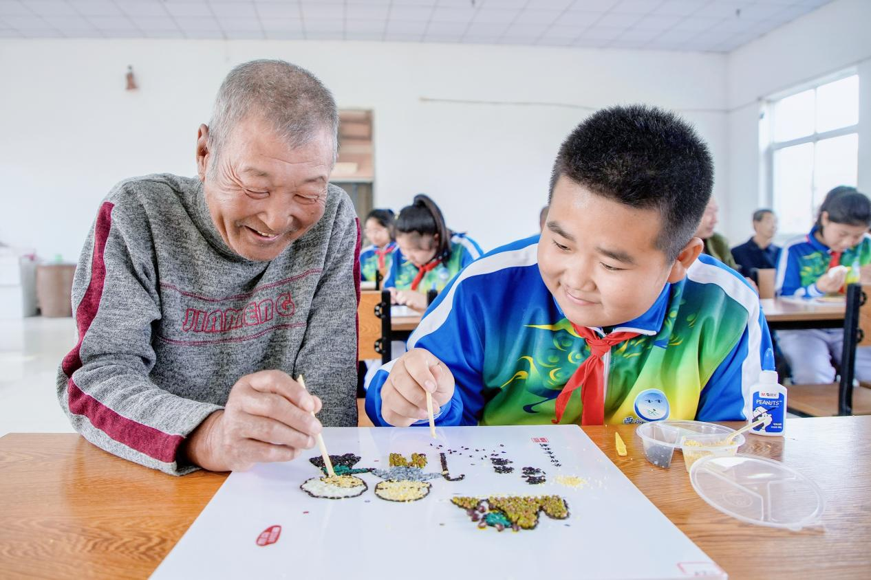 唐山市豐南區西河小學學生與敬老院的老人一起粘貼五谷畫。 李福政攝