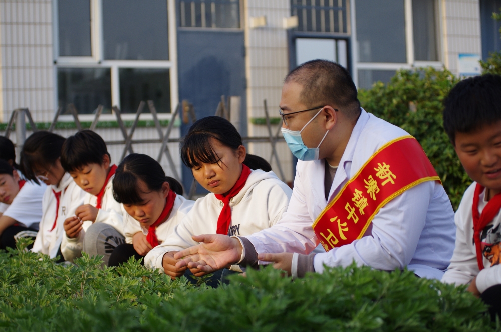 在乐亭县新寨镇三村小学种植园，医师刘槟榕在给学生介绍艾草驱虫的原理。 许海彬摄