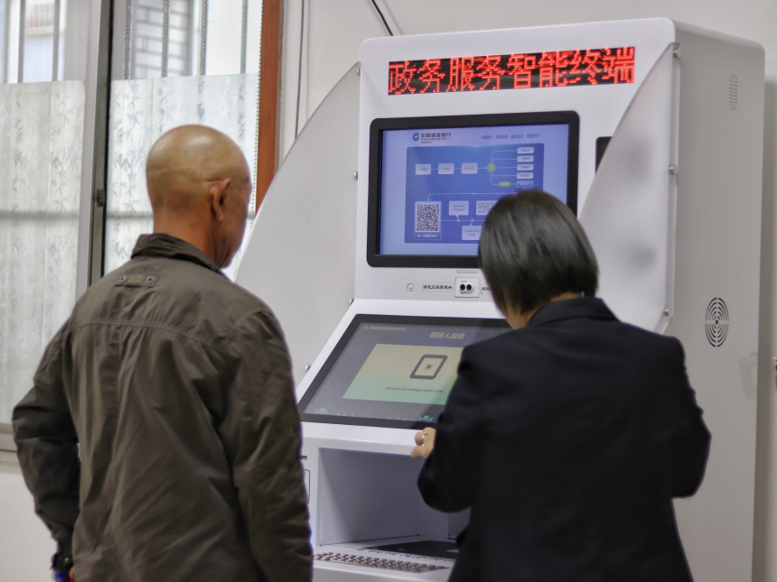 审批局工作人员帮助老人操作政务服务自助机。 张光伟摄