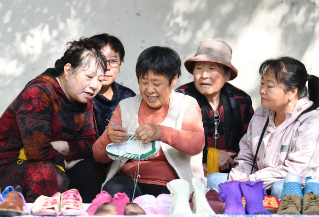 韓玉娥（中）向社區居民傳授毛線鉤織技藝。 劉江濤攝
