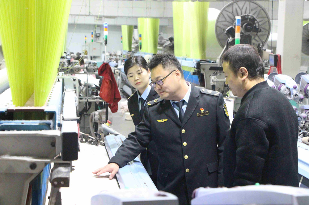 工作人員在紡織車間查看企業織造產品情況。 甄亞軍攝