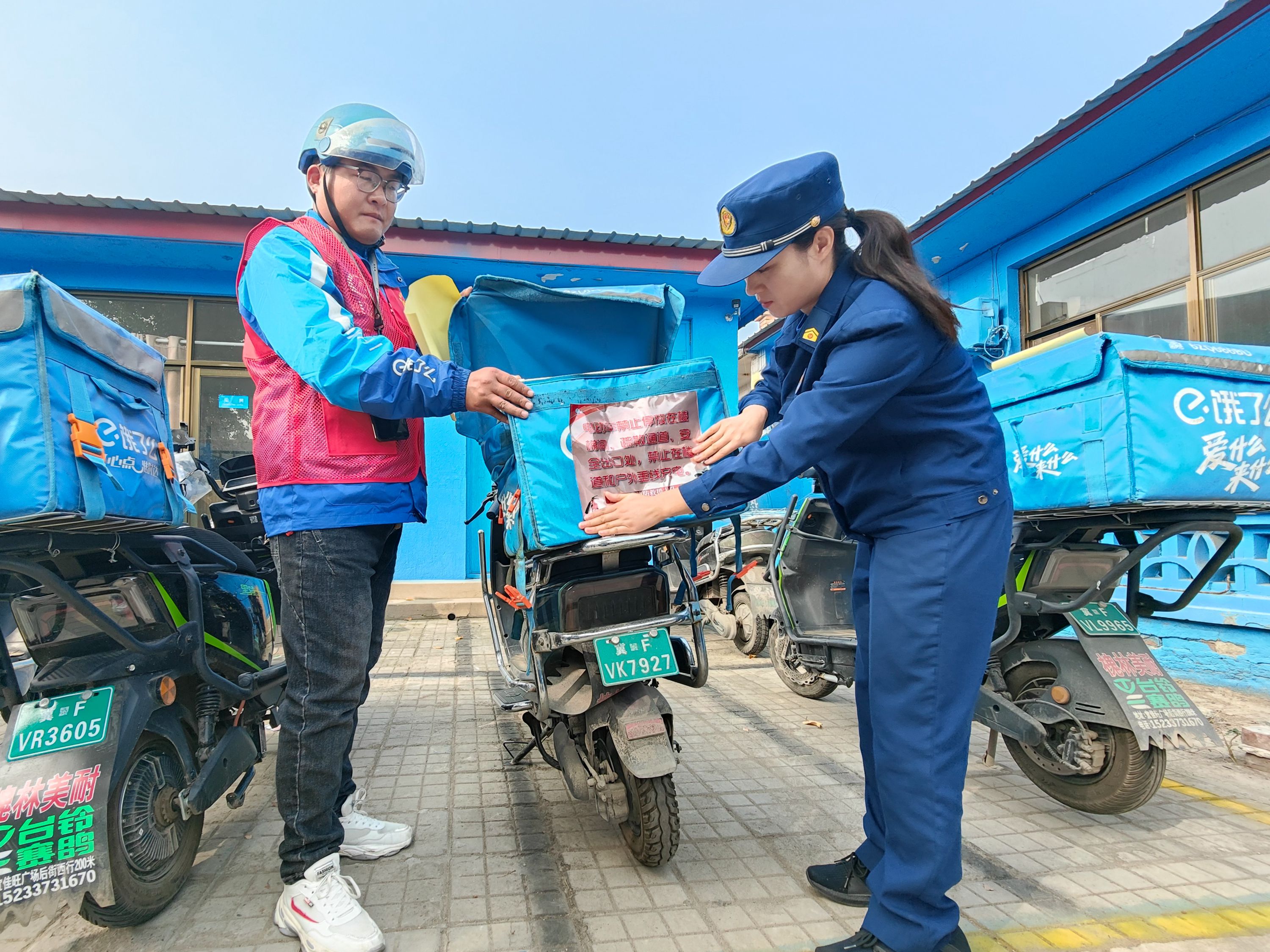 消防宣傳員將消防安全知識提示帖貼在外賣騎手的外賣箱上。 祖嘉誠攝