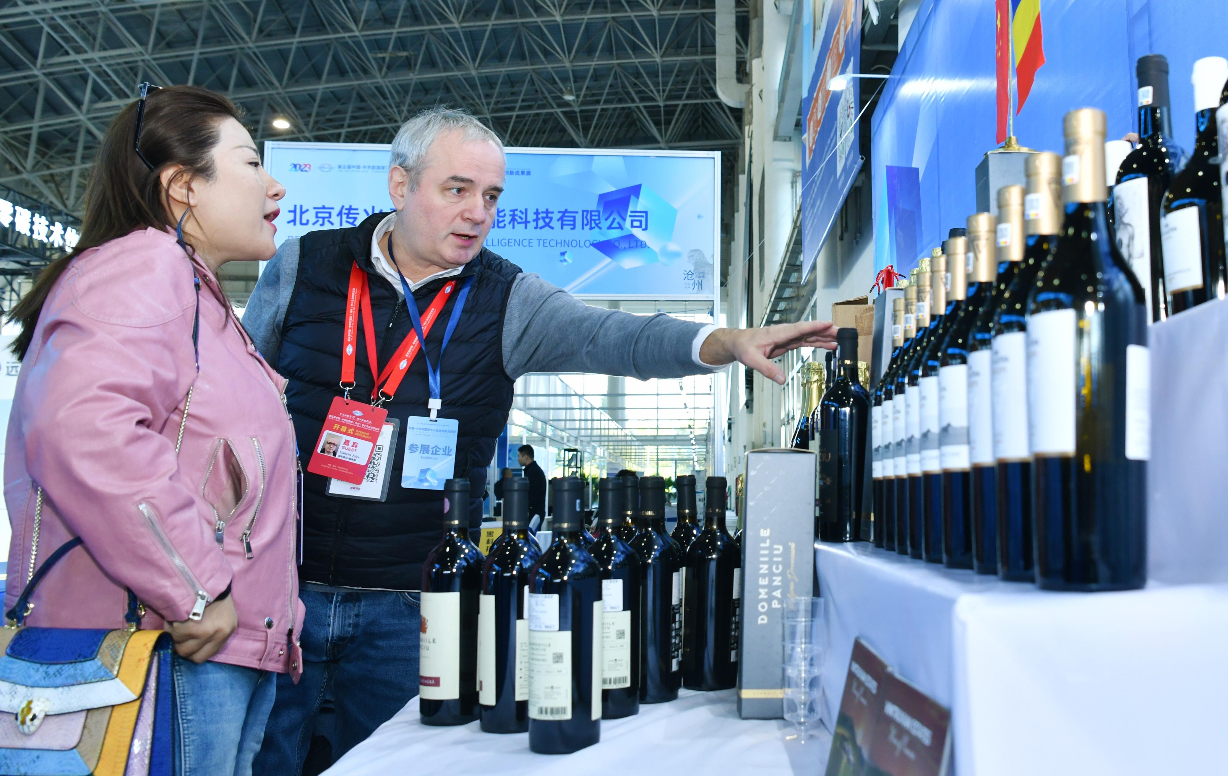 11月13日，来自罗马尼亚的参展商（右）向与会客商介绍红酒展品。 苑立伟摄