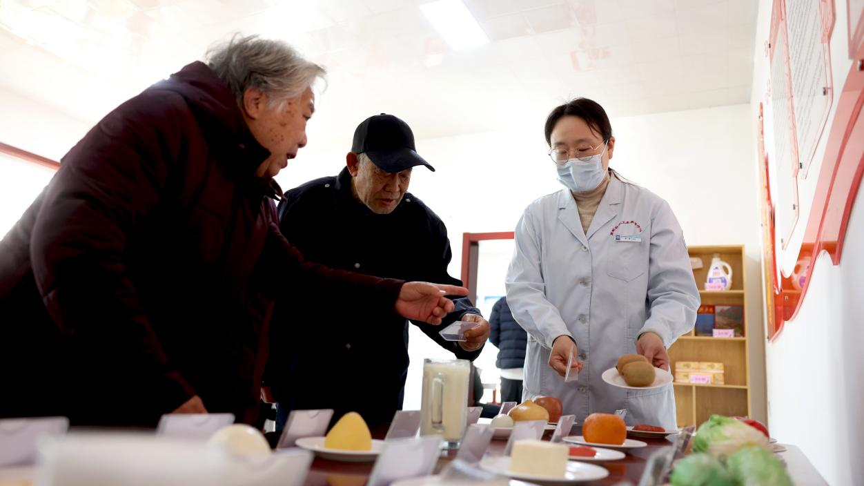 在活动现场，医生为老人介绍生活中常见食物的蛋白质、脂肪含量，鼓励老人养成健康饮食习惯。 杨晨摄