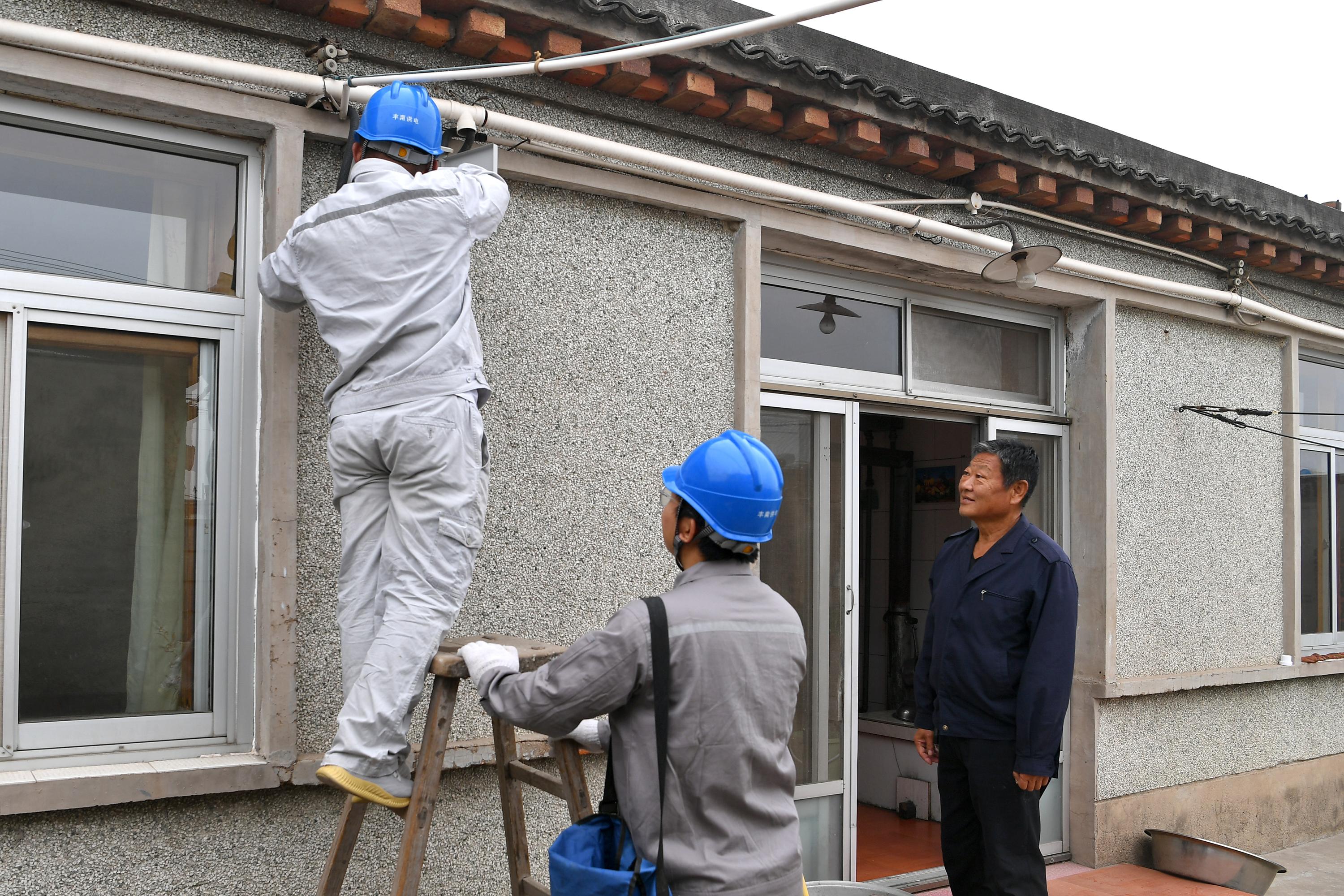 唐山市豐南區東田庄鄉供電所員工正在新庄子村村民家中檢查供暖低壓空氣開關設備。 劉浩學攝