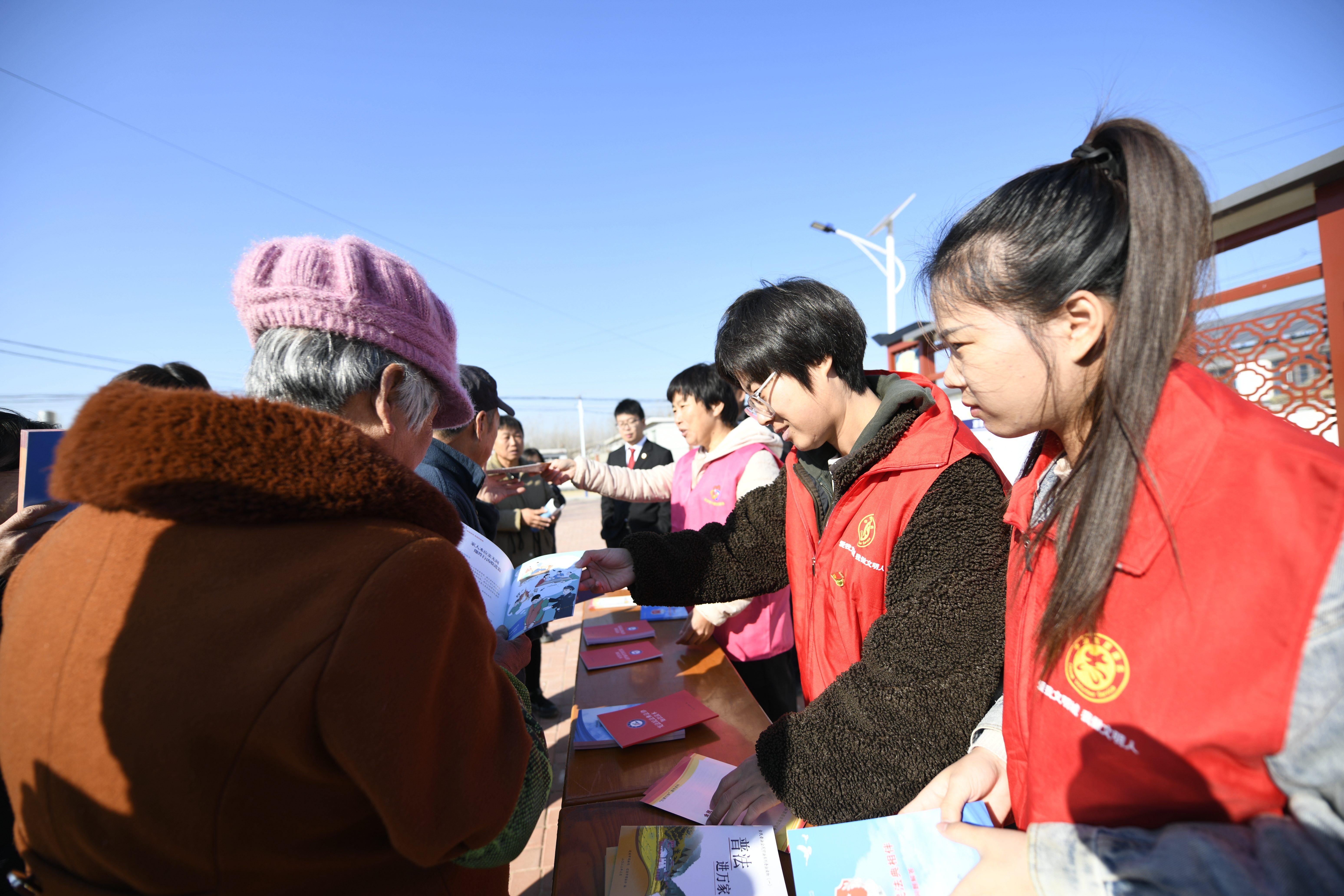 志愿者向村民发放《民法典》、网络诚信手册等宣传资料。 梁玉水摄