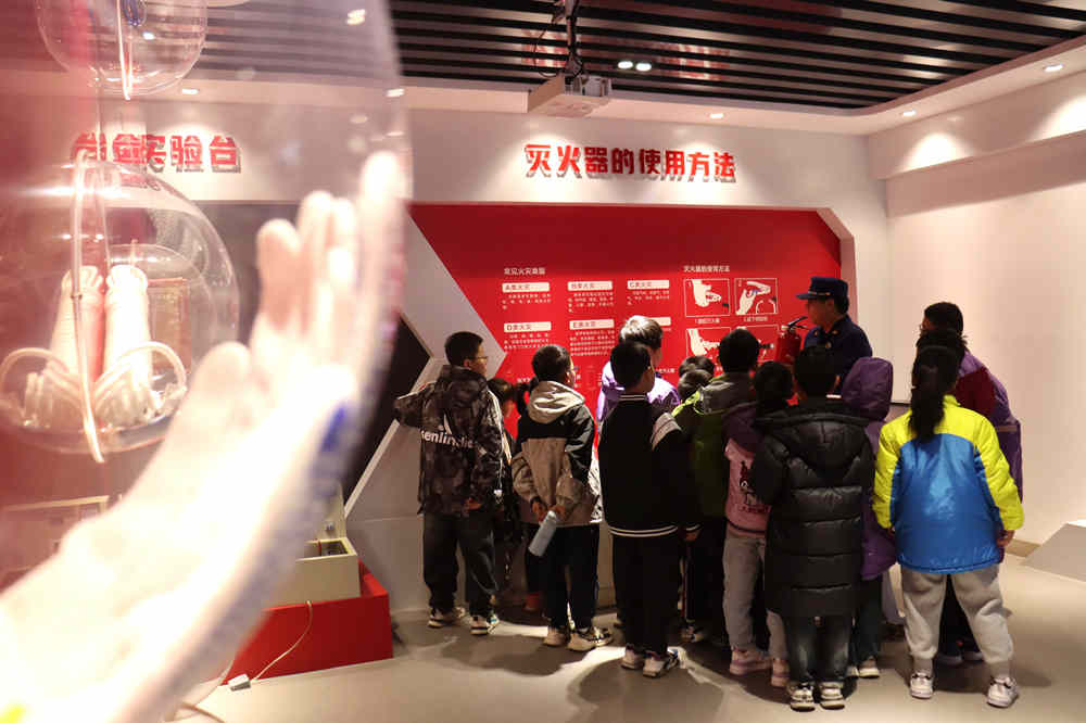 消防員帶領學生學習滅火器使用方法。 彭錦帥攝
