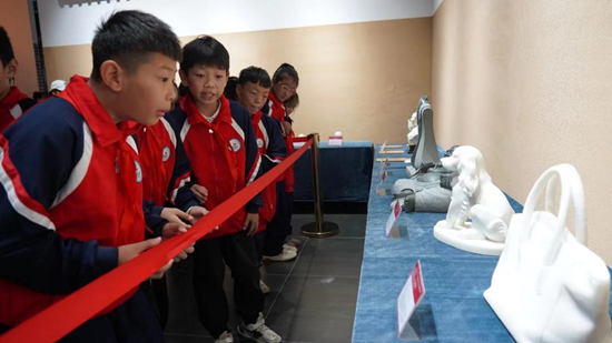 小学生在首届文化名家联展中欣赏雕塑作品。 唐笛摄